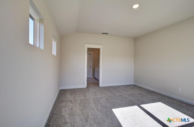 carpeted empty room featuring vaulted ceiling