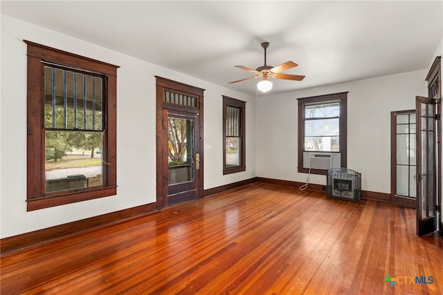 interior space featuring heating unit, cooling unit, a wood stove, hardwood / wood-style flooring, and ceiling fan