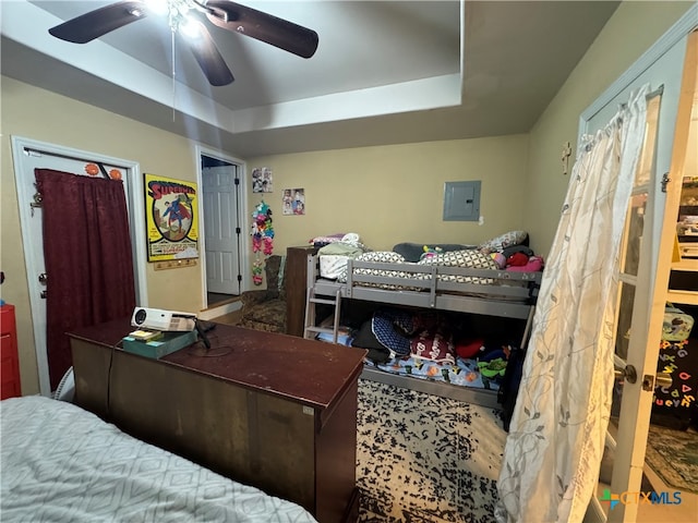 bedroom featuring electric panel, ceiling fan, and a tray ceiling