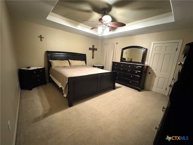 carpeted bedroom featuring ceiling fan, crown molding, and a tray ceiling