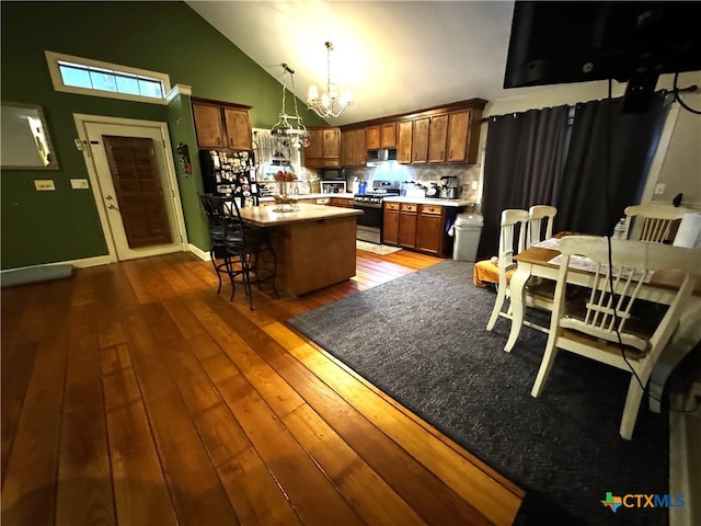 kitchen featuring stainless steel gas range, a kitchen bar, dark hardwood / wood-style floors, hanging light fixtures, and a center island