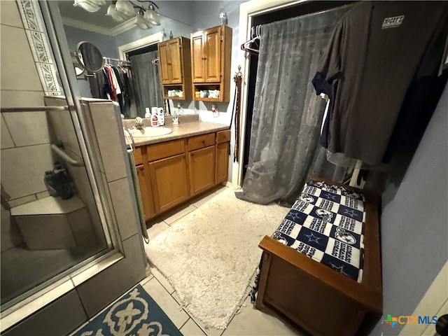 bathroom with a shower, vanity, tile patterned floors, and ornamental molding