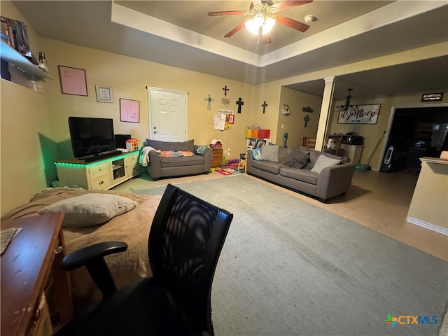 carpeted living room with ceiling fan and a tray ceiling