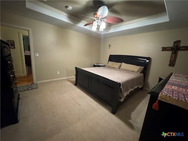 bedroom featuring ceiling fan, light carpet, a raised ceiling, and ornamental molding