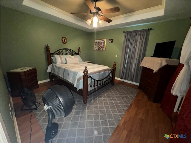 bedroom featuring a tray ceiling, ceiling fan, and dark hardwood / wood-style floors