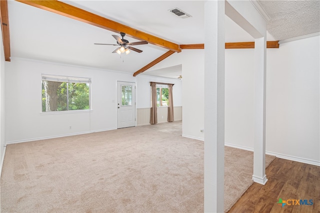 unfurnished living room featuring ceiling fan, crown molding, lofted ceiling with beams, and carpet floors