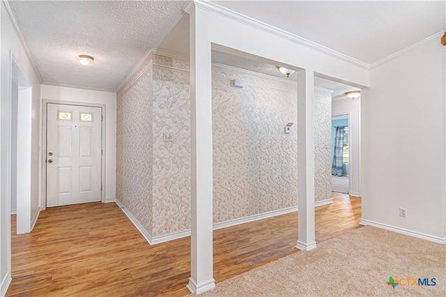 entryway featuring a textured ceiling, ornamental molding, and light hardwood / wood-style flooring