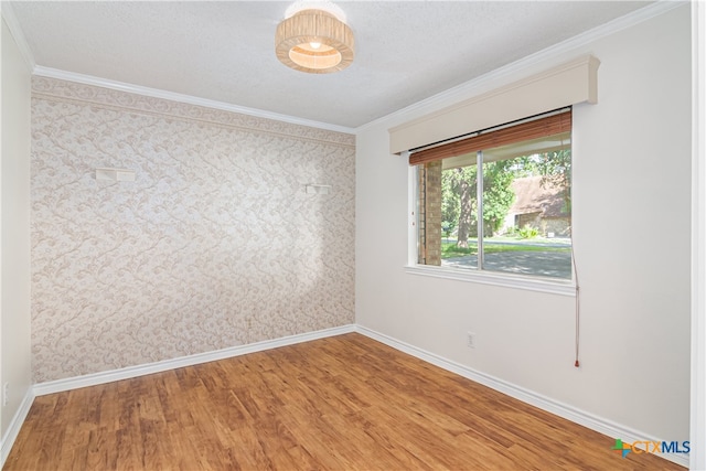 empty room featuring wood-type flooring and crown molding