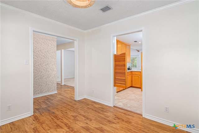 spare room featuring light hardwood / wood-style floors, a textured ceiling, and ornamental molding