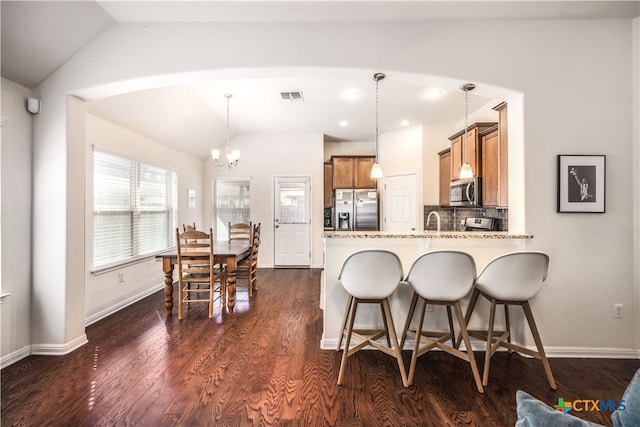 kitchen featuring lofted ceiling, decorative light fixtures, appliances with stainless steel finishes, and dark hardwood / wood-style flooring