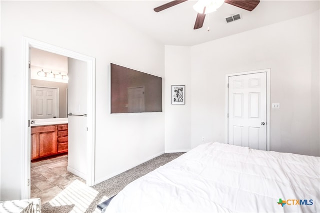 carpeted bedroom with ensuite bathroom and ceiling fan