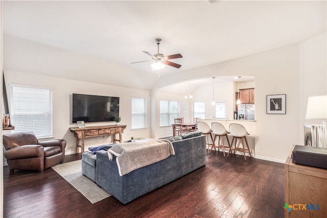 living room featuring vaulted ceiling, dark hardwood / wood-style floors, and ceiling fan with notable chandelier