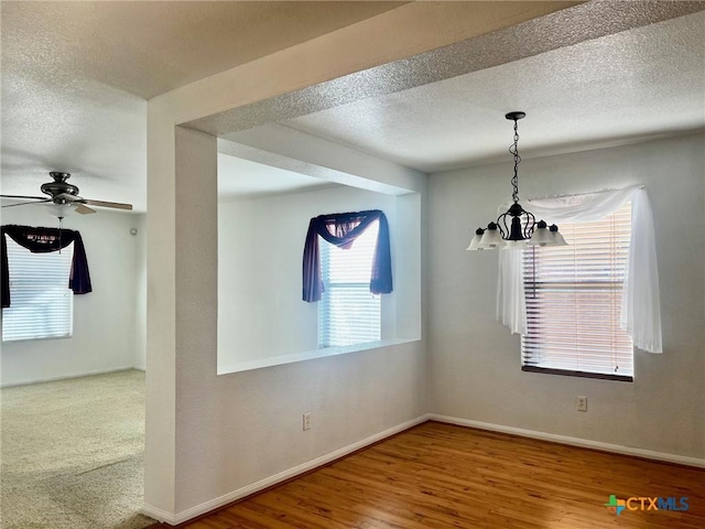 unfurnished room with a textured ceiling, hardwood / wood-style floors, and ceiling fan with notable chandelier