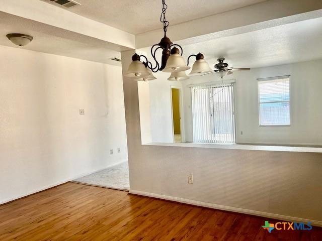 unfurnished room with hardwood / wood-style flooring and ceiling fan with notable chandelier