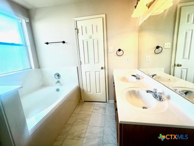 bathroom with vanity and a relaxing tiled tub