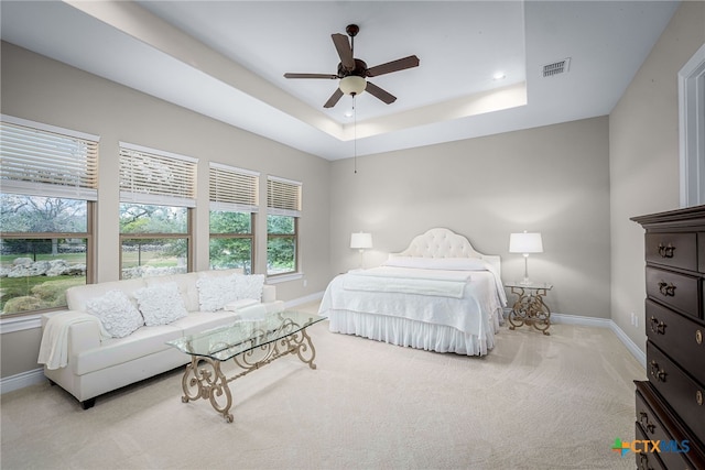 bedroom featuring baseboards, visible vents, and a tray ceiling