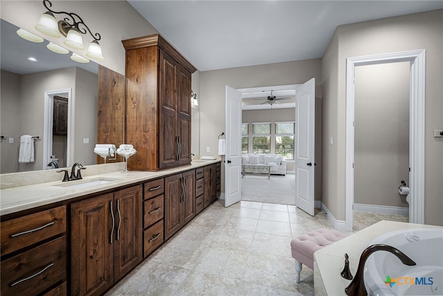 ensuite bathroom with double vanity, a bathing tub, ensuite bathroom, a sink, and baseboards