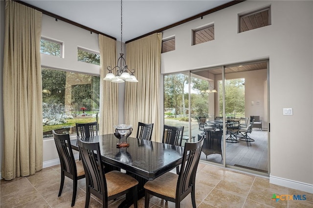 dining room with baseboards, a towering ceiling, and a notable chandelier