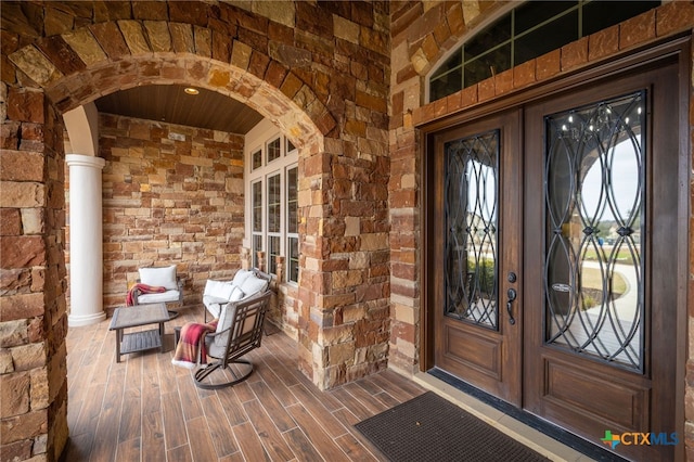 view of exterior entry with stone siding, french doors, and brick siding