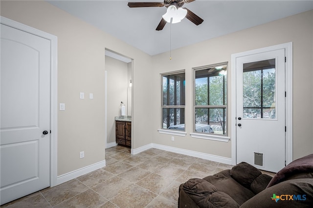 living area featuring baseboards and a ceiling fan