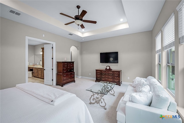 bedroom with a raised ceiling, light colored carpet, visible vents, and baseboards