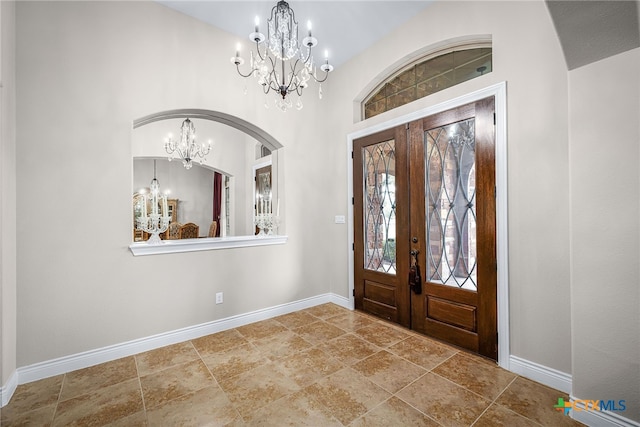 entrance foyer with a chandelier, french doors, and baseboards