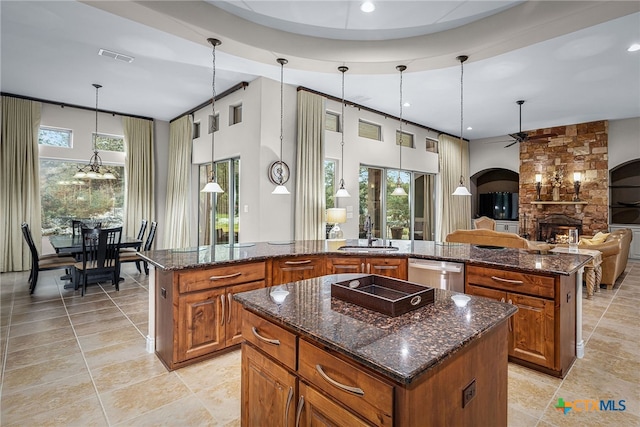 kitchen featuring a large island, brown cabinetry, a sink, and stainless steel dishwasher