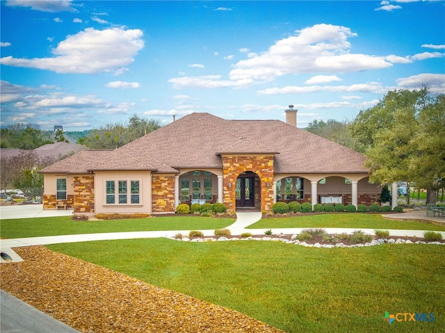 view of front of home with stone siding, a chimney, a front lawn, and stucco siding