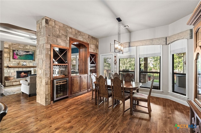 2299 Sun Chase Blvd, New Braunfels, TX 78130 - dining room featuring beverage cooler, a bar, dark wood-style floors, a fireplace, and a chandelier