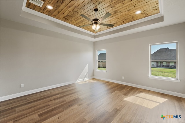 spare room with wooden ceiling, hardwood / wood-style flooring, a raised ceiling, and crown molding