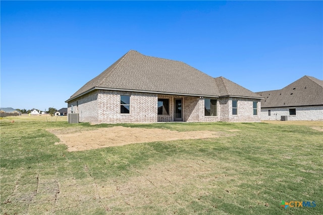 back of property with central AC unit and a yard