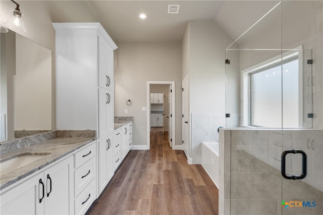 bathroom with wood-type flooring, vanity, separate shower and tub, and vaulted ceiling