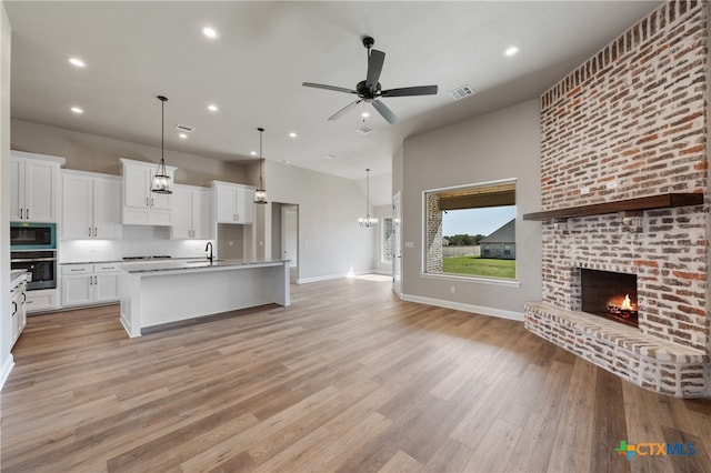 kitchen with white cabinetry, light wood-type flooring, a kitchen island with sink, and stainless steel appliances