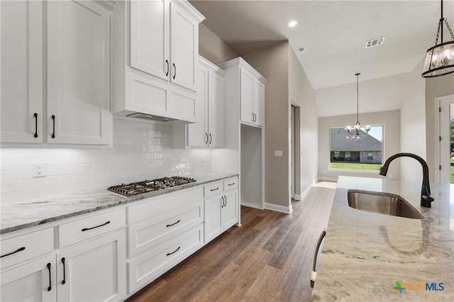 kitchen with white cabinetry, sink, hanging light fixtures, stainless steel gas stovetop, and dark hardwood / wood-style flooring