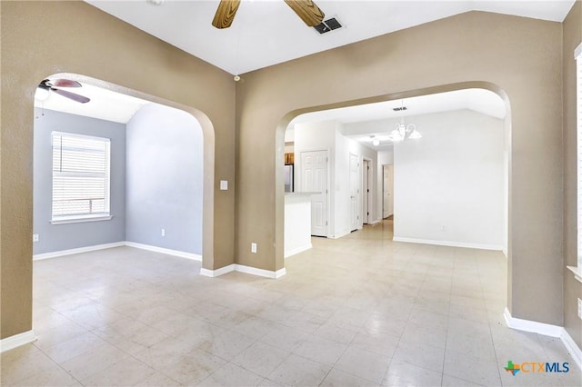 spare room with ceiling fan with notable chandelier and vaulted ceiling