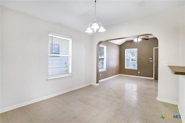 empty room featuring vaulted ceiling and ceiling fan with notable chandelier