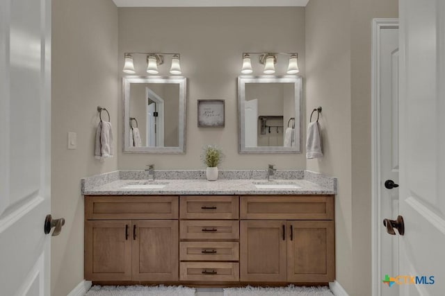 bathroom featuring baseboards, a sink, and double vanity