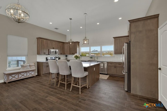 kitchen with stainless steel appliances, a center island, decorative backsplash, and an inviting chandelier