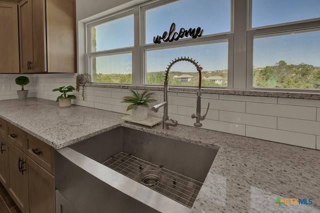 details featuring tasteful backsplash, light stone counters, and a sink