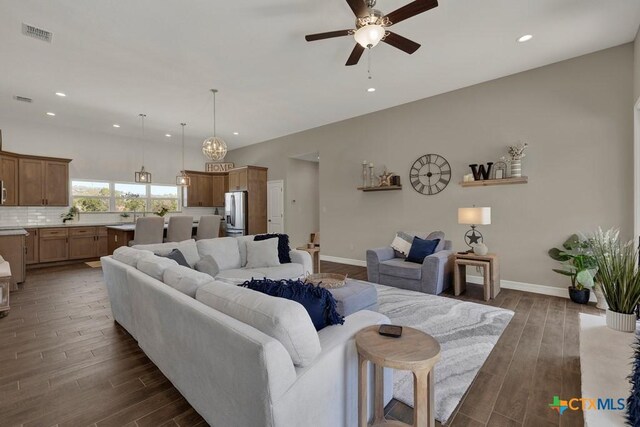 living area with dark wood-style flooring, a ceiling fan, visible vents, and baseboards