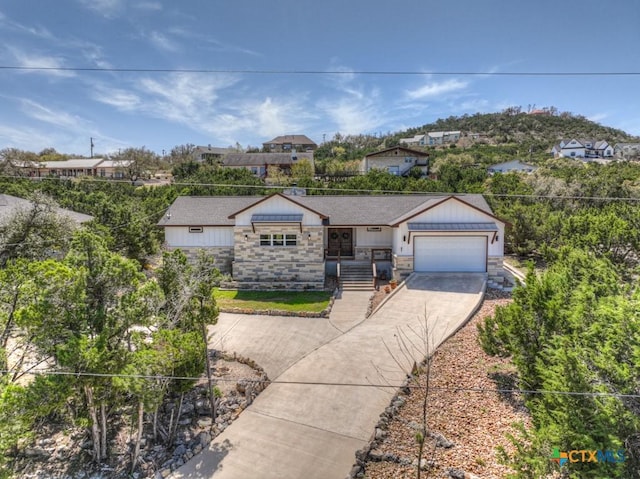ranch-style home with stone siding, driveway, board and batten siding, and a garage