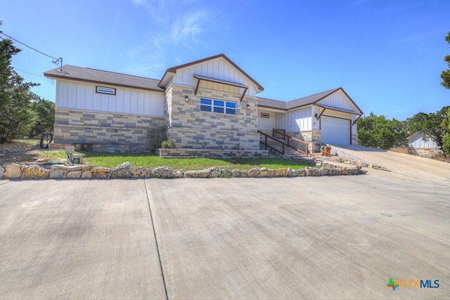 ranch-style home featuring stone siding, a garage, board and batten siding, and concrete driveway