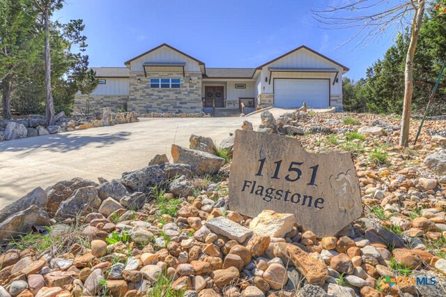 view of front of property with concrete driveway, stone siding, and a garage