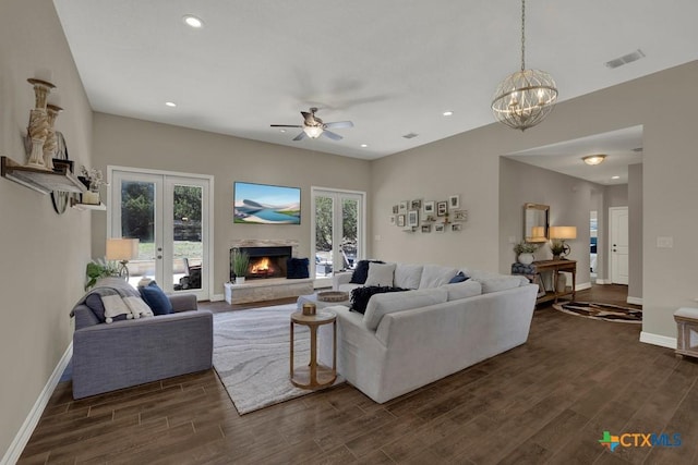 living room with ceiling fan with notable chandelier, baseboards, recessed lighting, and dark wood-style flooring