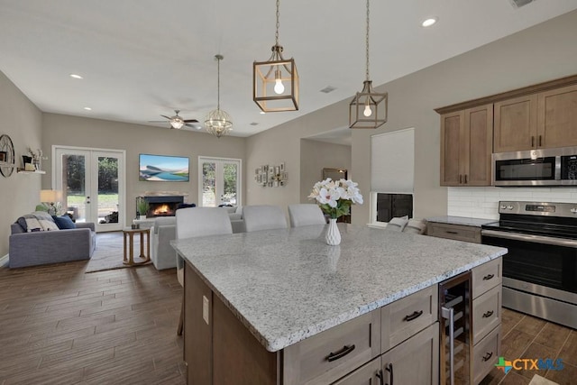 kitchen with dark wood finished floors, appliances with stainless steel finishes, open floor plan, and ceiling fan