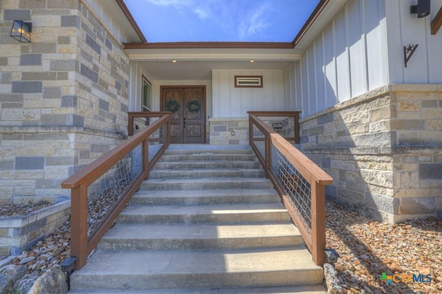 view of exterior entry with board and batten siding and stone siding