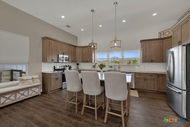 kitchen with a breakfast bar, decorative backsplash, a center island, and stainless steel appliances