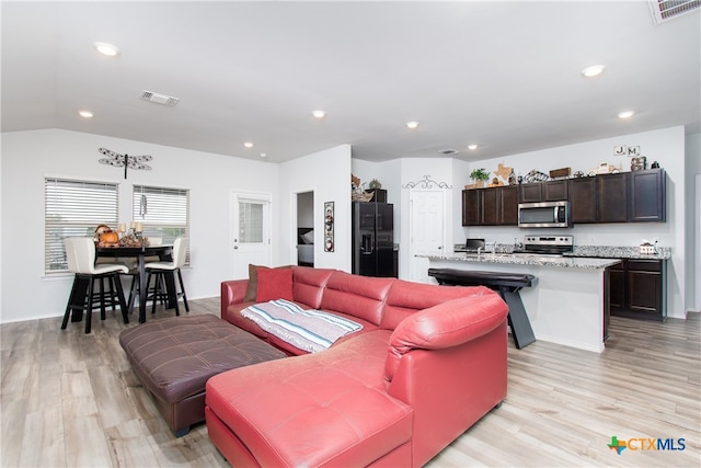 living room with light hardwood / wood-style flooring and vaulted ceiling