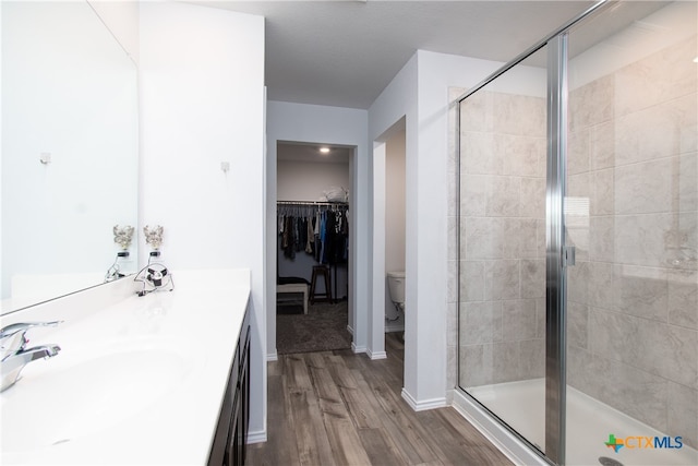 bathroom featuring hardwood / wood-style floors, an enclosed shower, vanity, and toilet