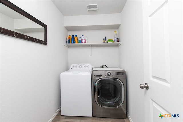 washroom featuring washing machine and clothes dryer and light hardwood / wood-style flooring